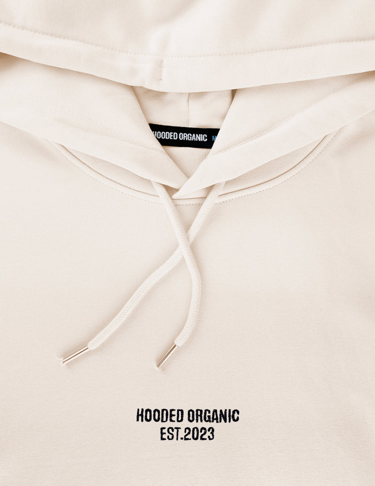 Detalje af beige hoodie med broderet Hooded Organic-logo – 100% økologisk bomuld