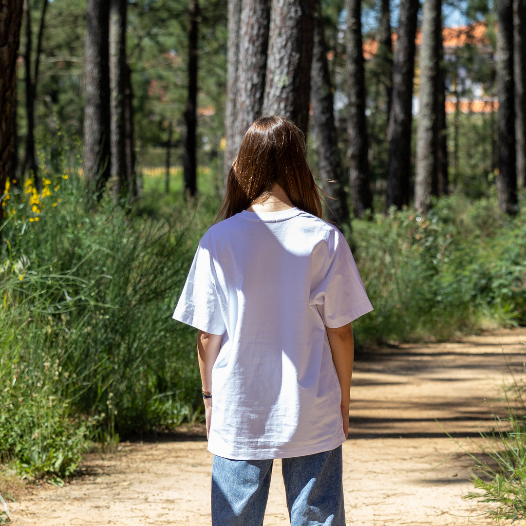 Hvid T-shirt med logo på kvindelig model set bagfra – loose fit og 100% økologisk bomuld
