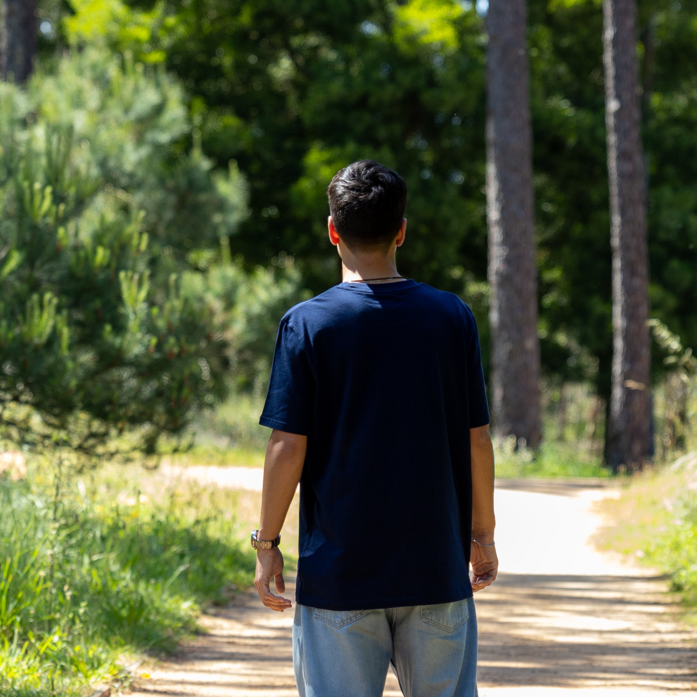 Mandelig model i navy blå blank T-shirt set bagfra – loose fit og 100% økologisk materiale
