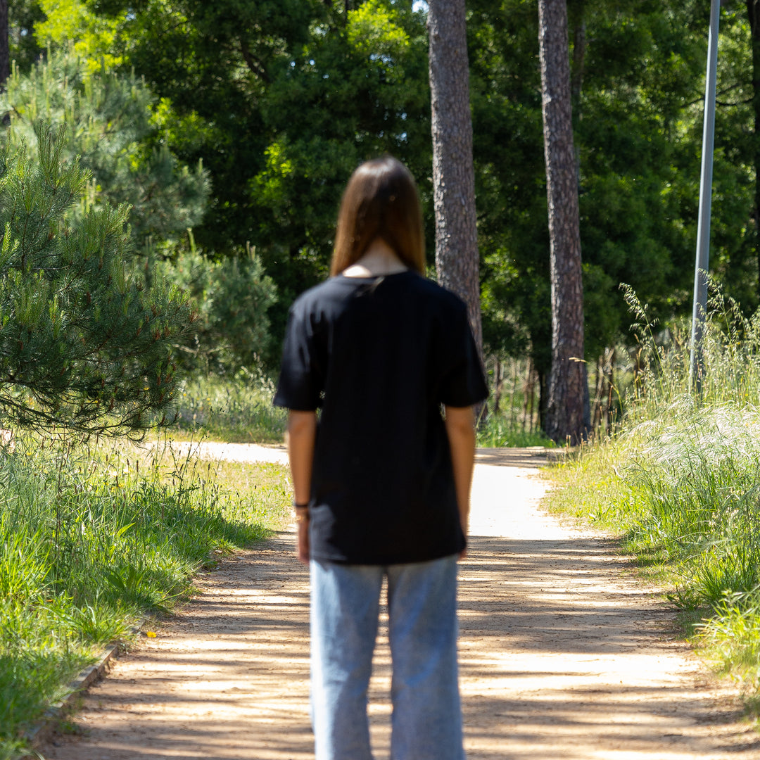Kvindelig model i sort T-shirt set bagfra – klassisk pasform i 100% økologisk bomuld
